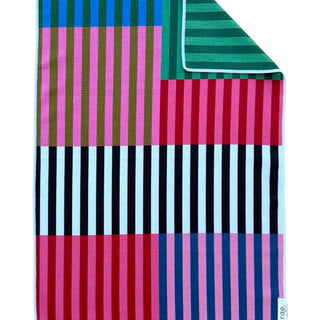 Reversible hand towel featuring colorful patchwork stripe panels in pink, green, red, navy, and white.