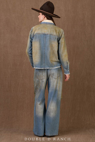 Woman wearing a distressed olive-washed denim workshirt with frayed hem, paired with wide-leg jeans and brown hat.