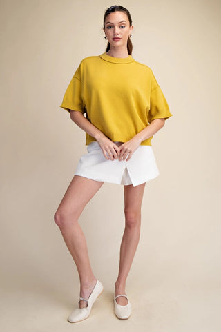 Mustard yellow cropped knit sweater with elbow-length sleeves, ribbed hem, and seam detail.