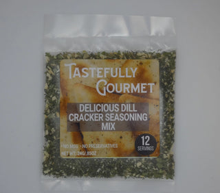 Small clear packet of Tastefully Gourmet Delicious Dill Cracker Seasoning Mix filled with green herb flakes.