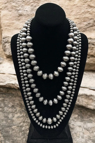 Four-strand Navajo pearl necklace featuring graduated oxidized silver beads displayed on black jewelry bust.