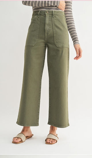 Olive green high-waist wide-leg jeans with large patch cargo pockets, worn with striped top and sandals.