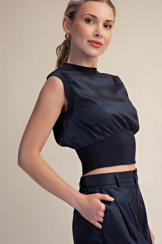Navy blue sleeveless crop top with mock neck, structured wide waistband, and satin fabric finish.