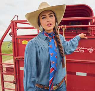 Blue and red striped scarf with equestrian saddle print, styled as a neck scarf on a woman in western attire.