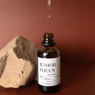 Amber glass dropper bottle of Junior Focus Saffron Tincture by Evergreen Apothecary, with golden liquid drop falling, beside 