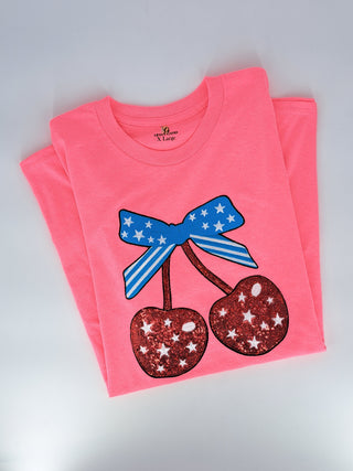 Neon pink XL t-shirt featuring sparkly red sequin cherries with patriotic blue star-print bow graphic.