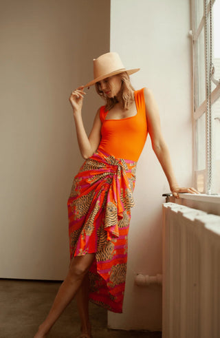 Vibrant orange and pink tiger-print pareo skirt tied at the waist, styled over an orange swimsuit.