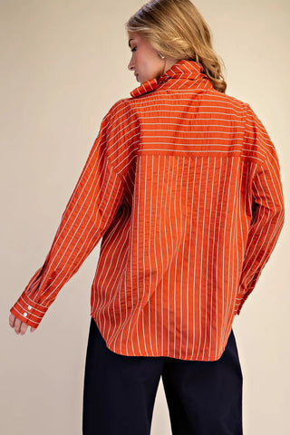 Orange and white striped high neck oversized button-up shirt with long sleeves, back view.