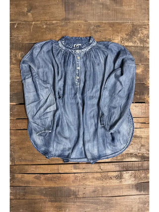 Wander Softly Top in faded blue chambray with ruffled neckline, half-button placket, and billowy long sleeves.