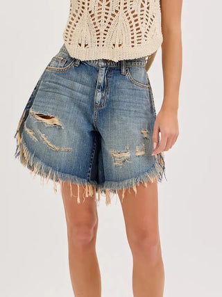 Mid waisted distressed denim cut off shorts with frayed hem, ripped details, and medium blue wash.