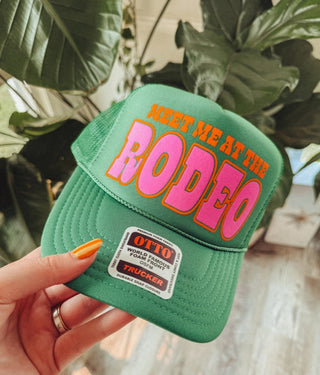 Green Otto foam trucker hat with bold pink and orange "Meet Me At The Rodeo" graphic text.