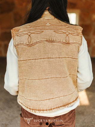 Beige embroidered denim vest with western stitch detailing, worn over white long-sleeve shirt, back view.
