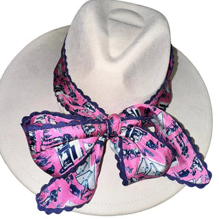 Pink and navy Cowboys and Indians print silk twilly scarf with navy rickrack trim, tied in a bow on a white felt cowboy hat.
