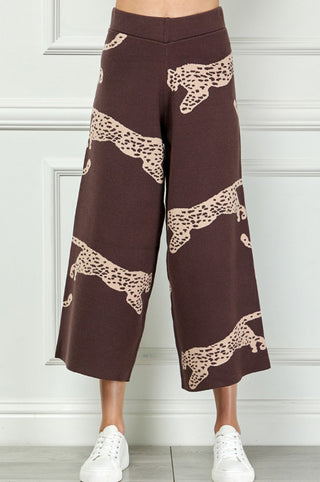 Dark brown wide-leg knit culottes featuring large beige leaping leopard print pattern, worn with white sneakers.