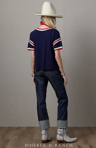 Navy blue short-sleeve top with red and white striped trim at collar and sleeves, worn with jeans and cowboy boots.