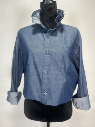 Blue chambray cropped button-down shirt with ruffled collar, rolled cuffs, and chest pocket on mannequin.