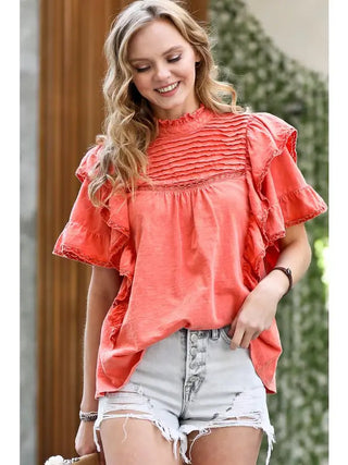 Coral orange vintage washed ruffle blouse with lace trim, mock neck, and tiered flutter sleeves.