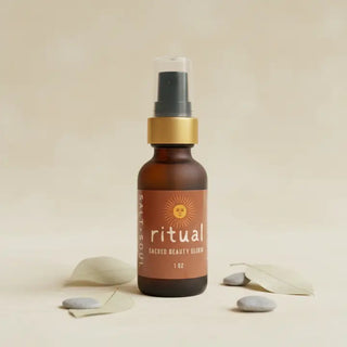 Amber glass pump bottle of Salt + Soul Ritual Sacred Beauty Elixir face oil, surrounded by eucalyptus leaves and smooth stone