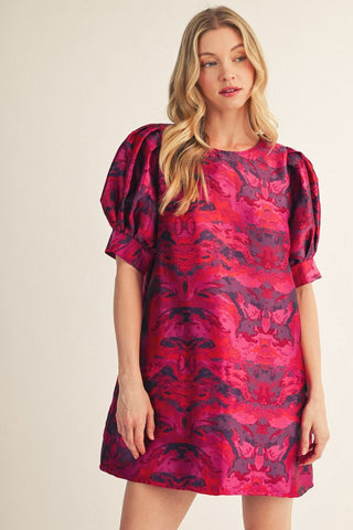 Fuchsia and purple jacquard print mini dress with puff sleeves and round neckline on model.