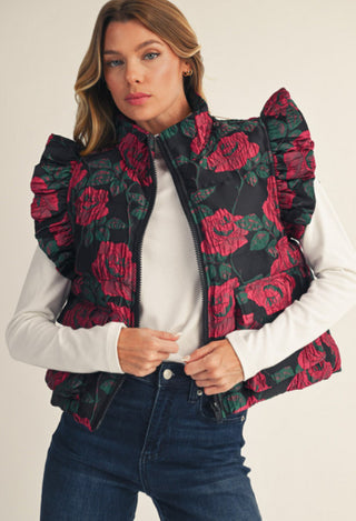 Black floral jacquard puffer vest with red roses, ruffled cap sleeves, and front zip closure.