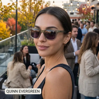 Quinn Evergreen sunglasses with translucent olive-gray frames and purple-tinted lenses, worn at an outdoor rooftop gathering.