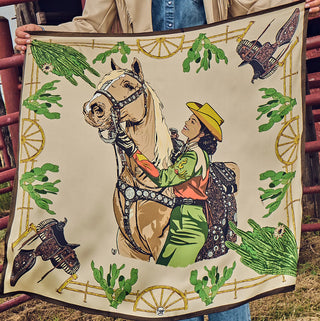 Bone-colored western silk scarf featuring cowgirl on palomino horse, cactus border, wagon wheels, and decorative spurs.