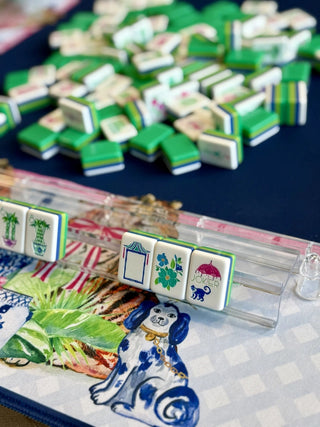 Blue and white chinoiserie tiger print mahjong mat with green mahjong tiles and acrylic rack displayed on top.