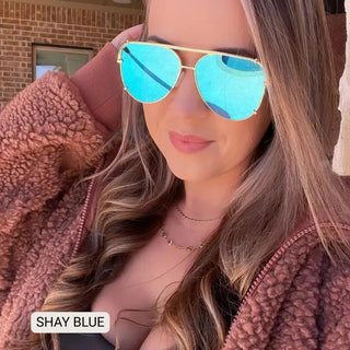 Woman wearing Shay polarized aviator sunglasses with blue mirrored lenses and gold metal frames outdoors.