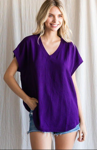 Purple v-neck cap sleeve top with raw edge hems, paired with distressed denim shorts.