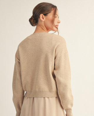 Beige drop-shoulder knit sweater with soft texture and ribbed hem, shown from back view.